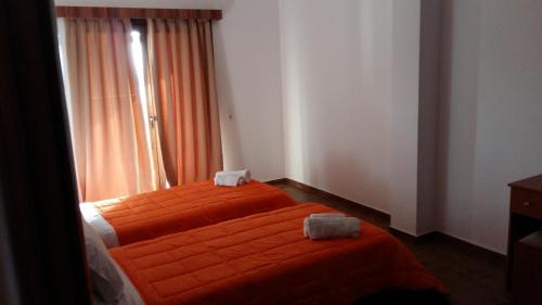 a bedroom with two beds with orange sheets and a window at Villa Molivos Castle in Mithymna