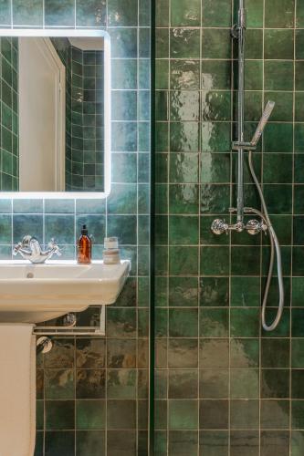 a green tiled bathroom with a sink and a mirror at Brand New! Valletta Boutique Style Apartment in Valletta