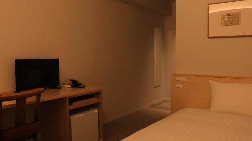 a bedroom with a bed and a desk with a television at Shin-Osaka Station Hotel in Osaka
