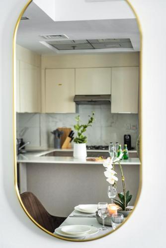 a mirror reflecting a kitchen with a table with wine glasses at Stella Stays Lana Tower in Dubai