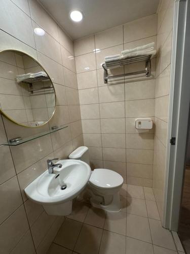 a bathroom with a sink and a toilet and a mirror at Shuang Shuang in Tainan