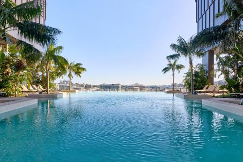 a large swimming pool with palm trees and buildings at The Star Grand Brisbane in Brisbane