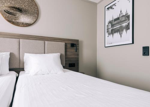 a bedroom with two beds and a mirror on the wall at Best Western Plus Kalmarsund Hotell in Kalmar