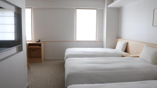 a hotel room with two beds and two windows at Shin-Osaka Station Hotel in Osaka