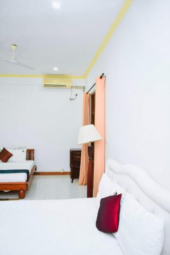 a white bedroom with a bed and a lamp at Hotel Sobana Lake front in Udawalawe