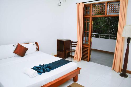a bedroom with a bed and a desk and a window at Hotel Sobana Lake front in Udawalawe