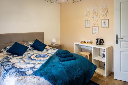 a bedroom with a bed with blue pillows and a desk at Comme une evidence in La Chapelle aux Pies
