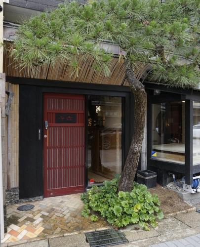 a tree in front of a building with a red door at ワインとお宿千歳Chitose in Monju