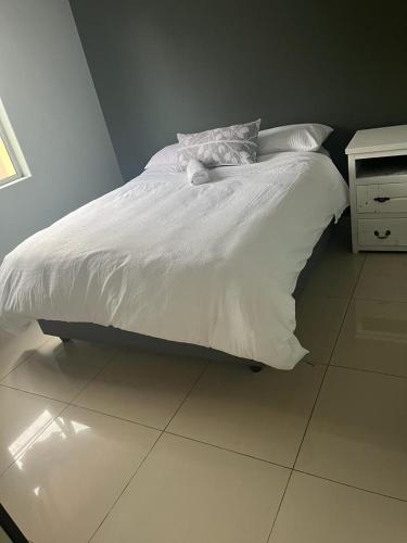a bed with white sheets and pillows on it at West Coast comfortable stays in Cape Town