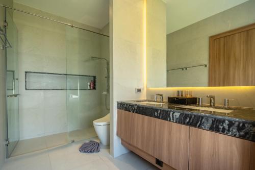 ein Badezimmer mit Dusche, Waschbecken und Toilette in der Unterkunft Mouana Breeze Maikhao 3-bedroom Pool Villa in Mai Khao Beach