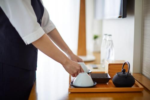 a person holding a tea kettle on a table at Keio Plaza Hotel Tokyo Premier Grand in Tokyo
