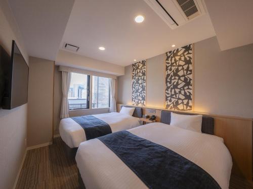 a hotel room with two beds and a window at Hotel SUI Kyoto Kiyomizu in Kyoto