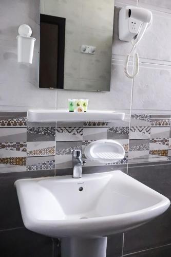 a bathroom with a white sink and a mirror at AL MARSA HOTEL APARTMENTS in Khor Fakkan