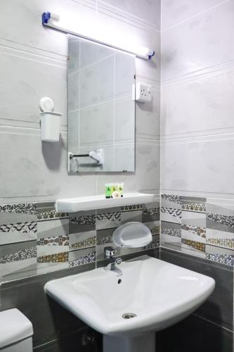 a bathroom with a white sink and a mirror at AL MARSA HOTEL APARTMENTS in Khor Fakkan