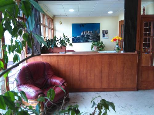 a waiting room with a red leather chair in front of a counter at Hotel Yeste in Yeste