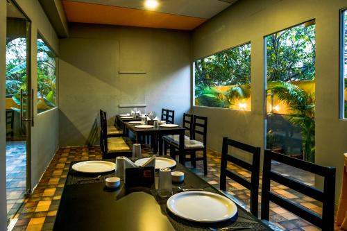 a dining room with tables and chairs and large windows at Treebo Breeze Way, Rushikonda in Visakhapatnam
