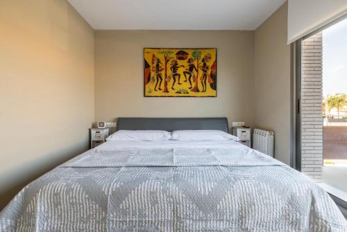 a bedroom with a large bed with a painting on the wall at Villa Vidalet solo familias in Cambrils