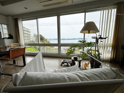 a living room with a couch in front of a large window at 熱海 無二荘 絶景オーシャンビュー ピアノ Bbq 三階建て貸切宿 in Atami