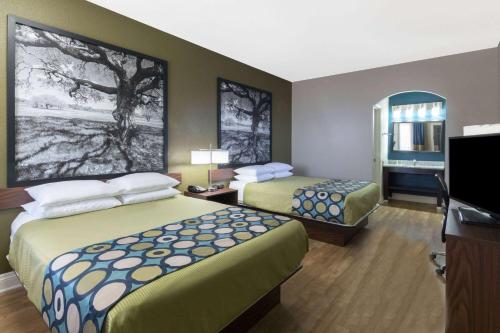 a hotel room with two beds and a flat screen tv at Super 8 by Wyndham San Antonio Near Fort Sam Houston in San Antonio