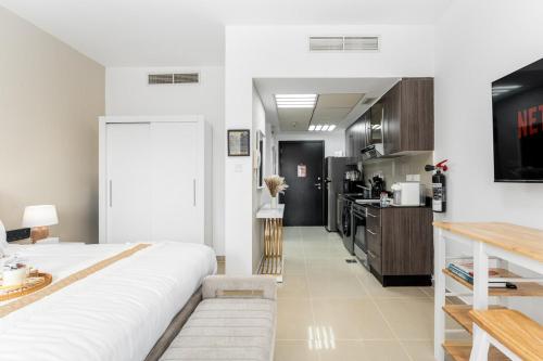 a bedroom with a large white bed and a kitchen at Smart Home with Alexa Near Yas and Airport with Pool in Abu Dhabi