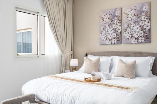a white bedroom with a large white bed and a window at Smart Home with Alexa Near Yas and Airport with Pool in Abu Dhabi