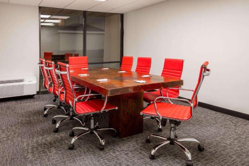 a conference room with a wooden table and red chairs at Ramada by Wyndham Austin South in Austin