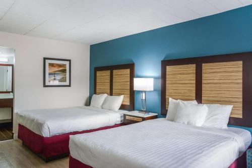 two beds in a hotel room with blue walls at Rodeway Inn Milford in Milford