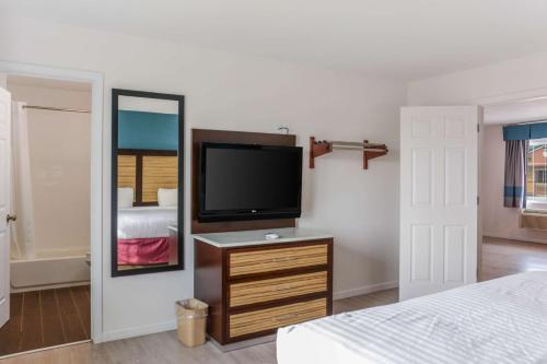 a bedroom with a flat screen tv and a bed at Rodeway Inn Milford in Milford