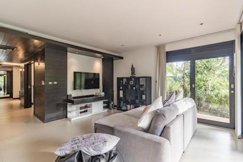 a living room with a couch and a tv at Le Oasis - 3BR Beachfront HOME in Laguna & Layan Beach next KORA Resort in Phuket