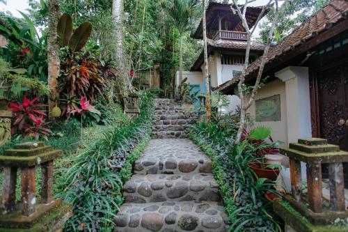 a garden with a stone path leading to a house at The Mahogany Villa Ubud in Tegalalang