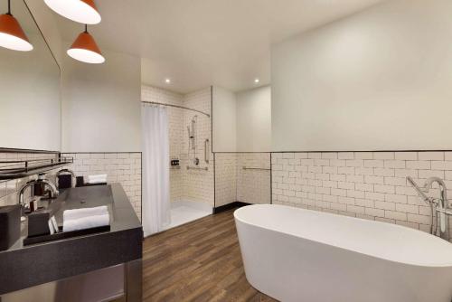a white bathroom with a tub and a sink at Origin Westminster a Wyndham Hotel in Westminster