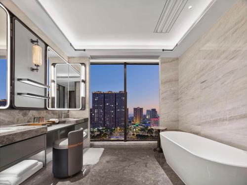 a bathroom with a tub and a large window at Hilton Yuyao in Yuyao