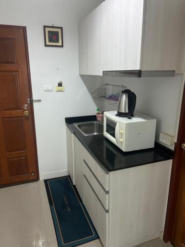 a small kitchen with a microwave and a sink at Baan Klang Condo in Hua Hin in Hua Hin