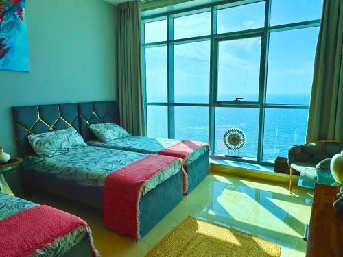 a bedroom with two beds and a large window at Luxury Corniche Residence 2 BHK pool gym wifi sea front in Ajman 