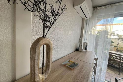 un vase avec une plante sur une table dans l'établissement Appartement Jardin Piscine Proche de la mer, à Narbonne
