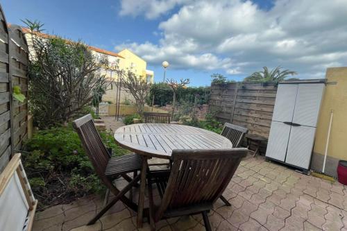 une table et des chaises en bois sur une terrasse dans l'établissement Appartement Jardin Piscine Proche de la mer, à Narbonne