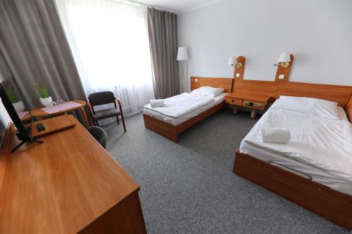 a hotel room with two beds and a desk at AGRO obiekt hotelowy in Wrocław