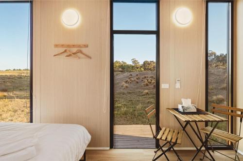 a bedroom with a bed and a table and a balcony at Rowsley Valley Tiny House 1 by Tiny Away in Ingliston