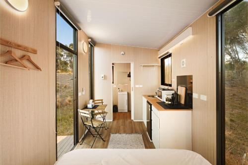 a room with a bed and a kitchen with a window at Rowsley Valley Tiny House 1 by Tiny Away in Ingliston