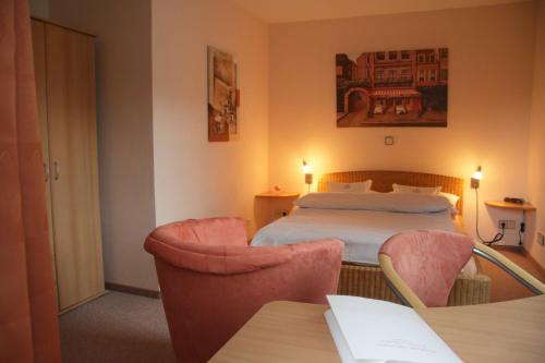a hotel room with a bed and two chairs at Rhönhotel Alte Mühle in Weyhers
