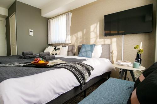 a hotel room with two beds and a flat screen tv at Mr Kintaro Higashikomagata in Tokyo