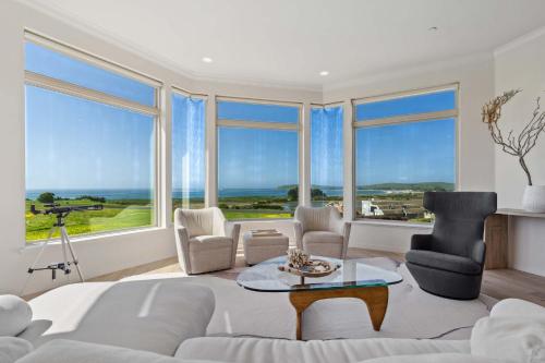 a living room with a couch and chairs and windows at Breathtaking Views of the Pacific Ocean Rooftop Balcony Gourmet Kitchen and Hot Tub overlooking Golf Course in Bodega Bay