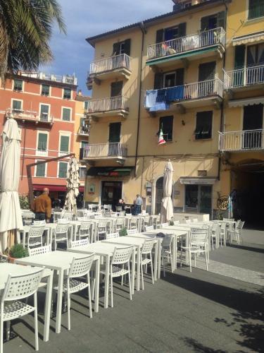 a group of white tables and chairs in front of a building at Golfo Dei Poeti Apartment in Lerici