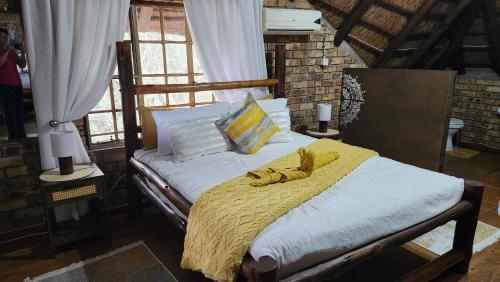 a bed with a yellow blanket and pillows on it at Parradys Marloth Park in Marloth Park