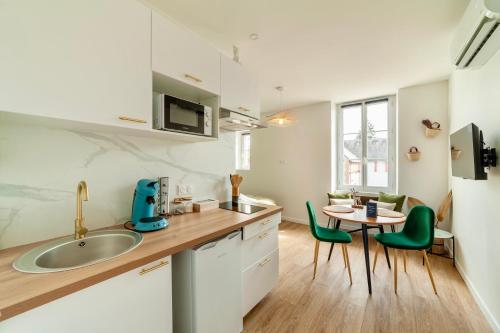 une cuisine avec un évier et une table avec des chaises vertes dans l'établissement La balade de Chambord, à Mont-près-Chambord