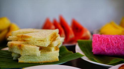 a stack of sandwiches on a green plate with fruit at Lake Island Home Stay in Dambulla