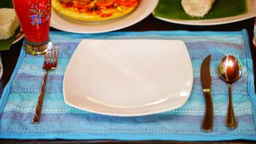 a table with a white plate and fork and knife at Lake Island Home Stay in Dambulla
