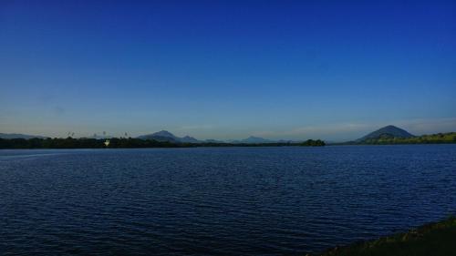 a large body of water with mountains in the background at Lake Island Home Stay in Dambulla