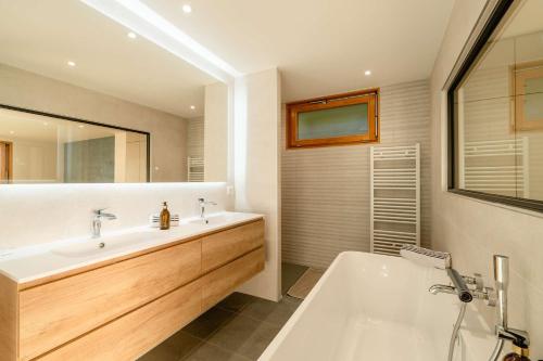 La salle de bains est pourvue d'une grande baignoire blanche et d'un lavabo. dans l'établissement Villa Sarmaz - vue lac, à Veyrier-du-Lac