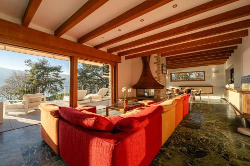 Elle comprend un salon doté d'un mobilier rouge et d'une grande fenêtre. dans l'établissement Villa Sarmaz - vue lac, à Veyrier-du-Lac